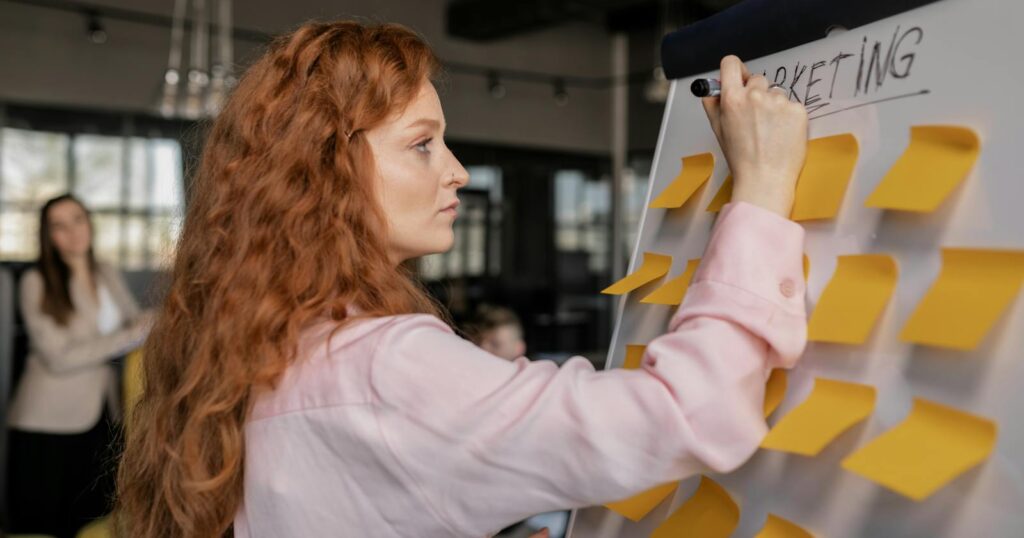 Photo of a Woman Writing on a Whiteboard with Sticky Notes